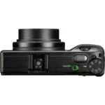 Top view of a compact digital camera with control dials and lens, available at Camix UK.