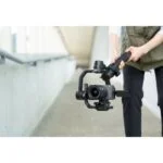 Person using a gimbal with a professional camera in a modern setting.
