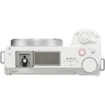 Top view of a white mirrorless camera body with control dials and buttons.