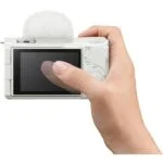 Person holding a compact digital camera with a flip screen, ideal for vlogging and photography.