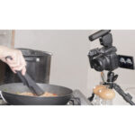 Canon camera on tripod filming cooking in kitchen.