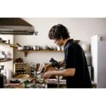 Person using a camera to film cooking in a kitchen, showcasing photography equipment.