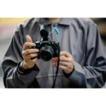 Person holding a Nikon mirrorless camera with a microphone attached.