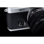 Close-up of a silver and black Olympus OM-3 camera with lens, showcasing photography equipment.