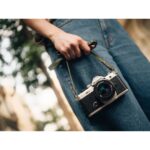 Person holding a vintage-style camera outdoors, showcasing photography gear.