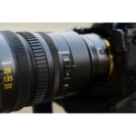 Close-up of a Nikon camera lens on a DSLR camera body, showcasing photography gear.