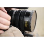 Close-up of a Nikkor 28-135mm power zoom lens held by a person, ideal for Nikon cameras and photography enthusiasts.