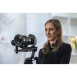 Woman using a professional camera on a stabilizer in a studio setting.