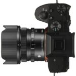 Top view of a mirrorless camera with a Sigma lens attached, showcasing camera controls and lens details.