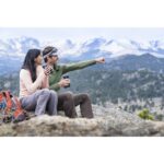 Couple with cameras enjoying mountain view, discussing photography gear.