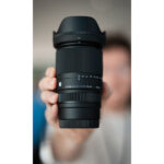 Person holding a Sigma zoom lens in a camera shop in the UK.
