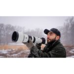 Photographer using a Sony telephoto lens on a snowy day, capturing wildlife.