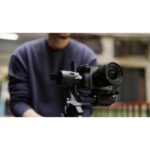 Person holding a mirrorless camera on a gimbal, showcasing photography equipment.