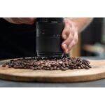 Person using Tamron lens to photograph coffee beans on wooden board.
