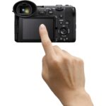 Person using touchscreen on a mirrorless camera, available at Camix UK.