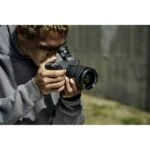 Person using a mirrorless camera outdoors, capturing a photo.