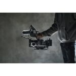 Person holding professional cinema camera with microphone and accessories.