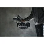 Person holding professional cinema camera with microphone and accessories.