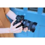 Person holding a Sony mirrorless camera with a zoom lens, ideal for photography enthusiasts.