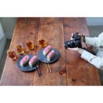 Person photographing desserts with a digital camera on a wooden table.