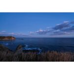 Scenic coastal view at sunset with cliffs and ocean waves.