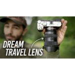 Man holding a mirrorless camera with a zoom lens outdoors.