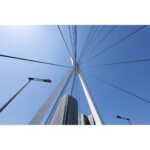 Modern bridge structure against a clear blue sky, viewed from below.