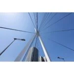 Modern bridge structure against a clear blue sky, viewed from below.