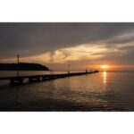 Sunset over a pier with calm waters, ideal for photography enthusiasts.