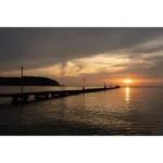 Sunset over a pier with calm waters, ideal for photography enthusiasts.