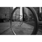 Urban scene with circular metal structures and tall buildings in black and white.
