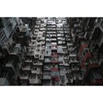 Tall residential building with numerous windows and balconies in an urban setting.