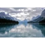 Scenic view of a tranquil lake surrounded by mountains under a cloudy sky.