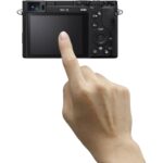 Hand touching the screen of a digital camera, showcasing camera features.