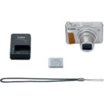 Canon compact camera with charger, battery, and strap on display.