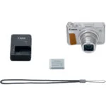 Canon compact camera with charger, battery, and strap on display.