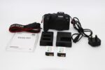 Canon EOS RP camera with accessories including batteries and charger.