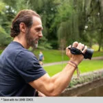 Man using a Panasonic camera outdoors in a park setting.