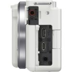 Side view of a white digital camera body with various ports and controls.