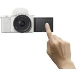 Sony mirrorless camera with flip screen and hand pointing, ideal for vlogging.