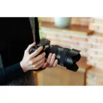 Person holding a mirrorless camera with a large lens in a camera shop.