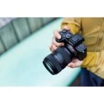 Person holding a Sony mirrorless camera with a Sigma lens, ideal for photography enthusiasts.