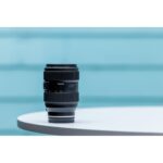 Tamron zoom lens on a white table, ideal for DSLR and mirrorless cameras.