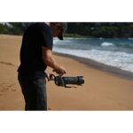 Photographer adjusting camera with telephoto lens on a beach