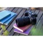 Canon EOS camera with lens on books, outdoor setting.