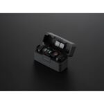 Compact camera accessory kit with wireless transmitters and charging case on black background.